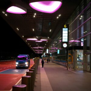 Night view of Singapore's Changi Airport entrance with illuminated canopy and bus.